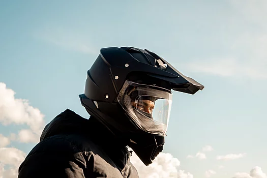 Motociclista che guarda in basso, indossando un casco con sotto un balaclava